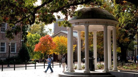A photo of a person walking by the Old Well