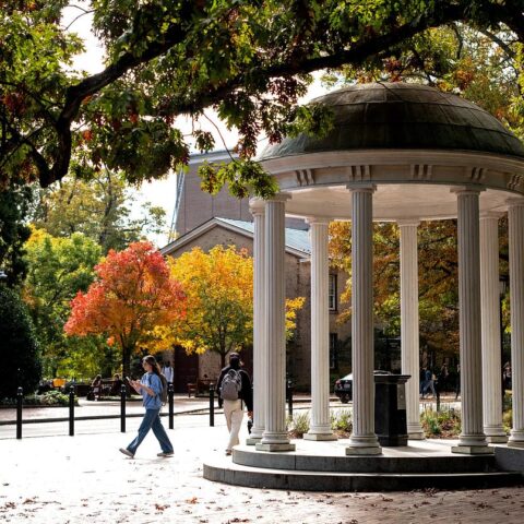 A photo of a person walking by the Old Well