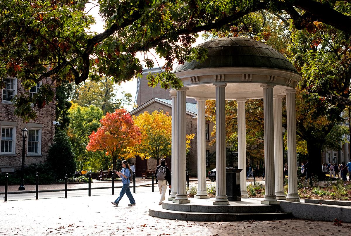 A photo of a person walking by the Old Well